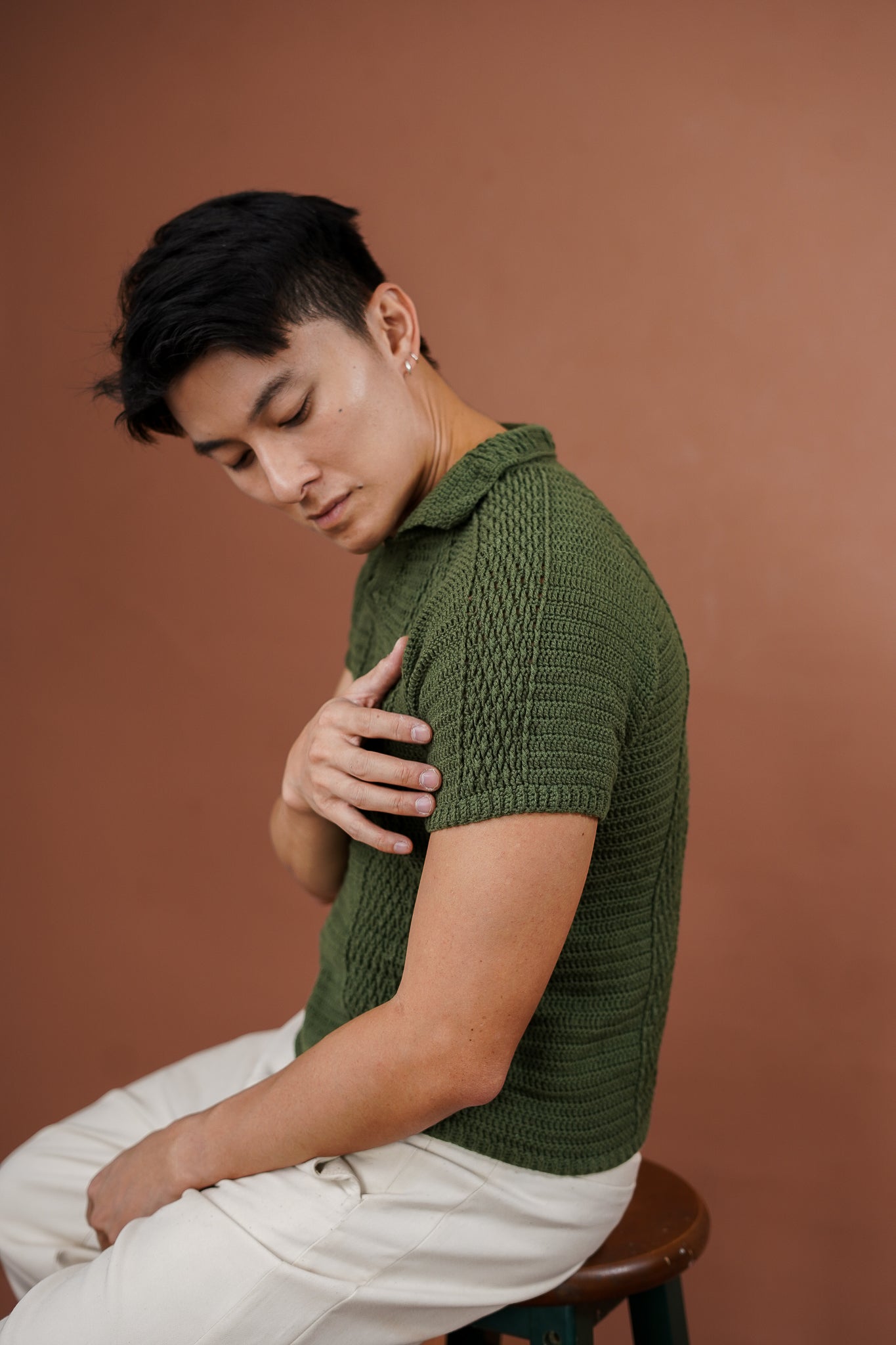 Man wearing a green crochet shirt against a brown background