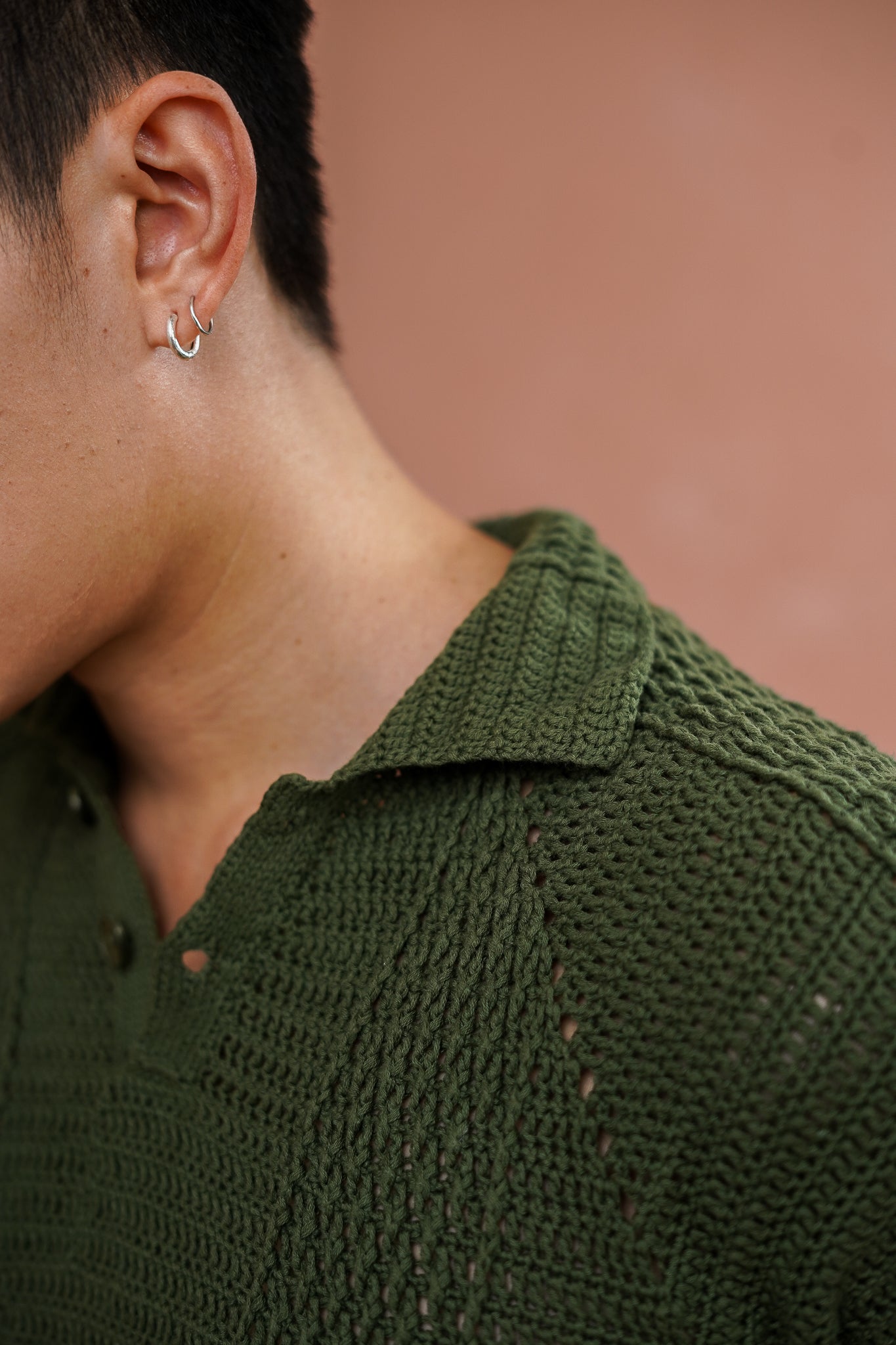 Person wearing a green crocheted shirt with a blurred background