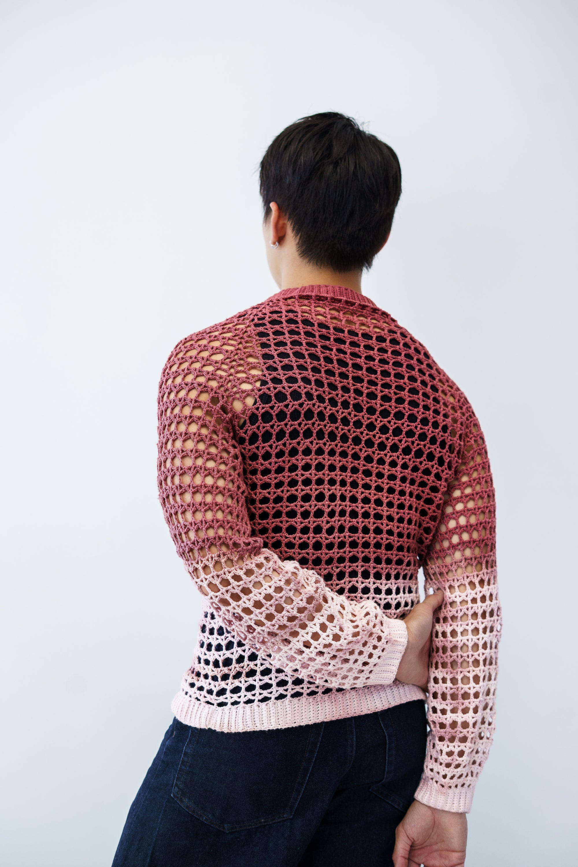 Man wearing a lace crochet sweater against a plain background