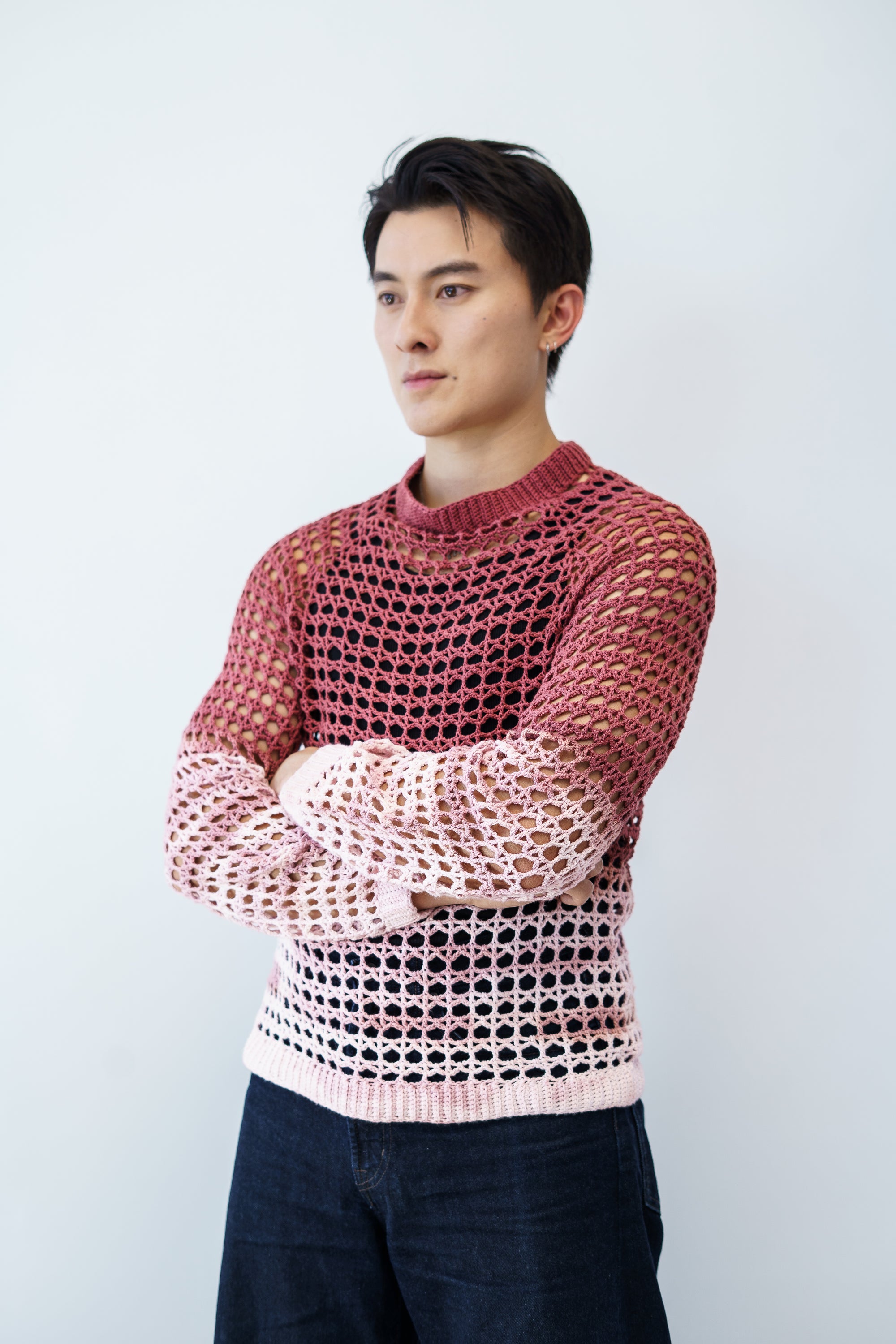 Person wearing a hand-dyed crocheted lace sweater with a white background