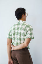 a man wearing a crochet shirt made with green and white granny squares